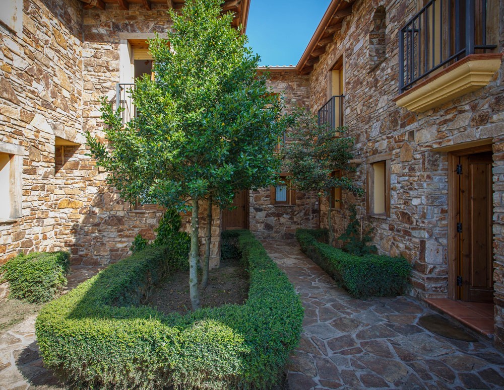 Patio con árboles en casa rural de piedras en Sierra de Madrid