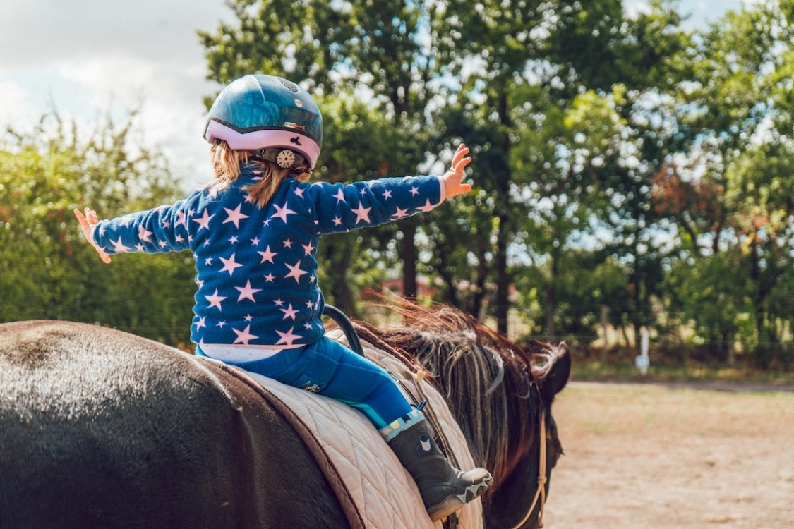 Niña montada a caballo con camiseta de estrellas