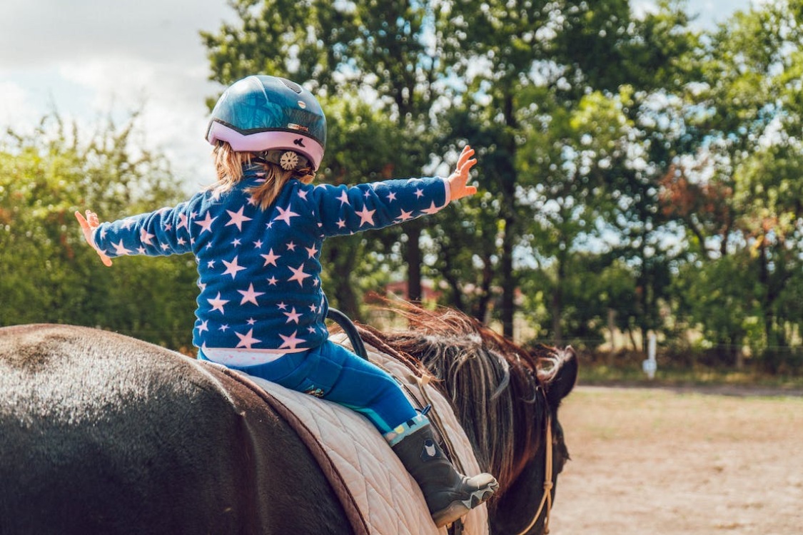 Niña montada a caballo con camiseta de estrellas