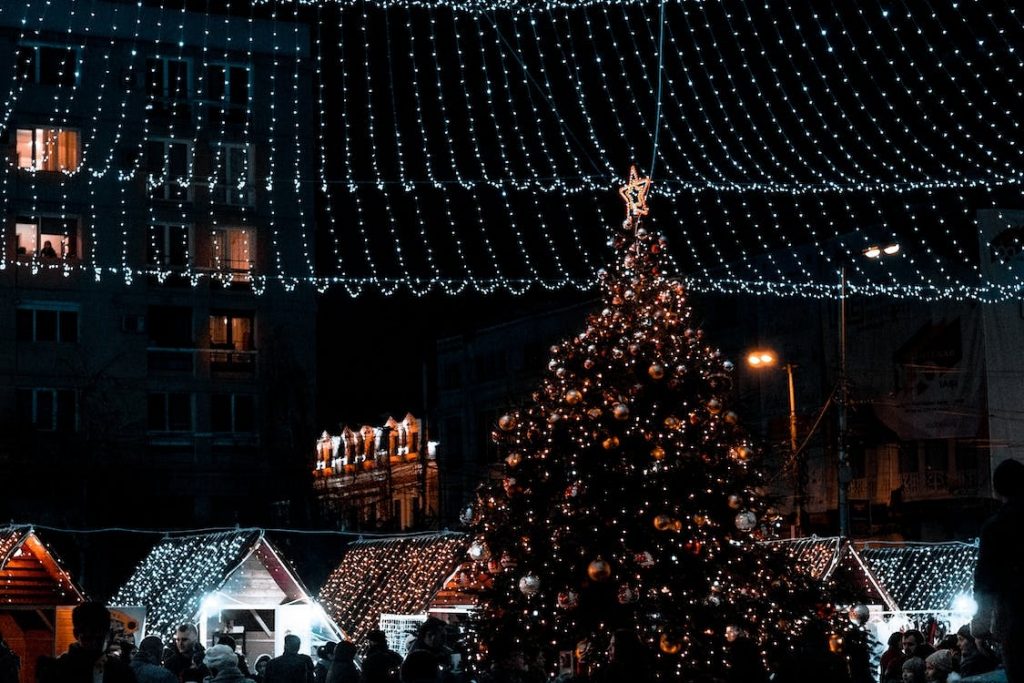 Mercadillo navideño donde se ven varios puestos, árbol de Navidad y luces de Navidad