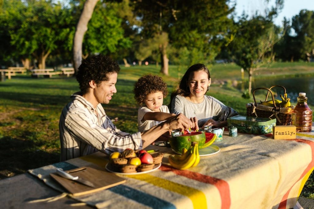 Padre, madre y niño en mesa con comida durante pícnic en la Sierra de Madrid