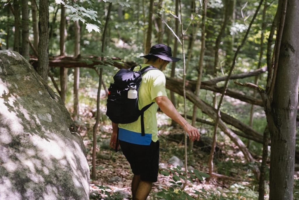 Hombre con gorro y mochila caminando por ruta de senderismo para principiantes en el bosque de la Sierra Norte de Madrid