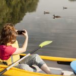 mujer en kayak y tomando fotos